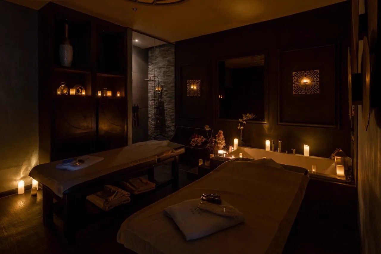 Candle-lit treatment room at Luxury SPA with warm lamps and a round backlit mirror